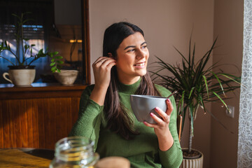 A young woman eating corn flakes for breakfast in the morning in her apartment	