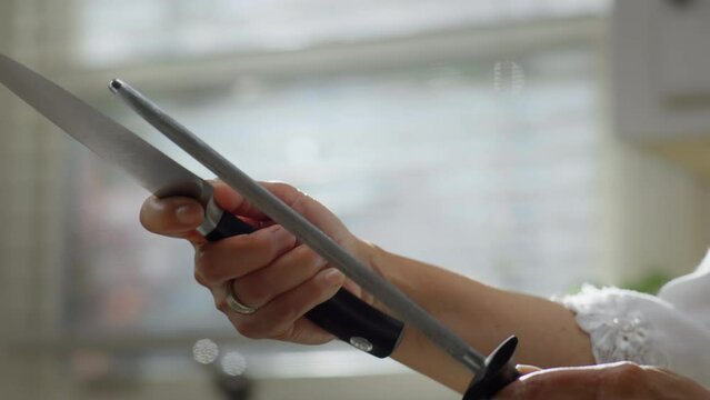 Closeup shot of an Asian woman sharpening a knife