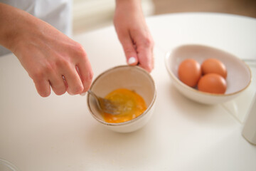 Close up of a woman's hands breaking eggs in the kitchen. Process of cooking pecan pie in home kitchen for American Thanksgiving Day.