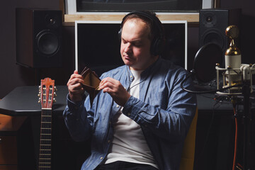 A musician in a recording studio holds an empty wallet in his hands. The workplace of a sound...