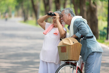 senior couple using binoculars and looking to something in the park