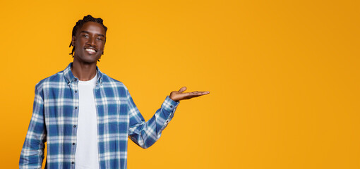 Happy Black Man Showing Invisible Object On Open Palm