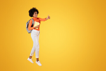 Fototapeta na wymiar Optimistic young woman with afro hair, in an orange top and white pants