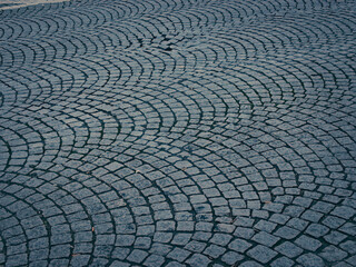 Heterogeneous uneven stone paving in the middle of the street. What the sidewalk is made of. In cloudy cool weather. Stone texture