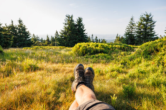 Crossed male legs with leather hiking boots. Relaxation in mountain forest during trekking