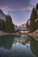 Grand mountain cliffs mirrored in serene alpine lake under evening sky 