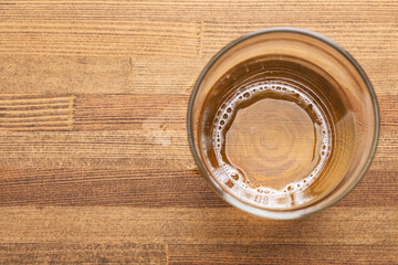 Nearly empty glass of beer on wooden table