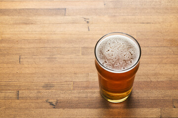 Craft beer in pint glass on a wooden table - obrazy, fototapety, plakaty