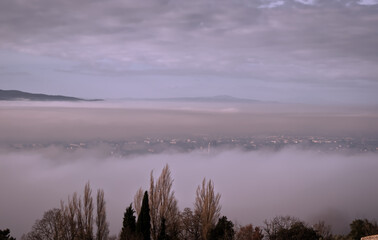 Valley surrounding the village of Assisi immersed in low clouds