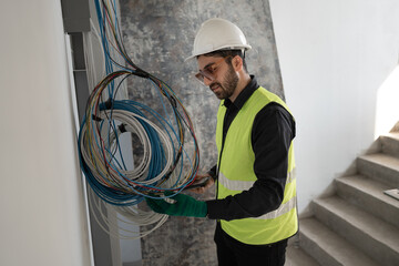 Hispanic Latin Electrical engineer man checking wires at construction site	