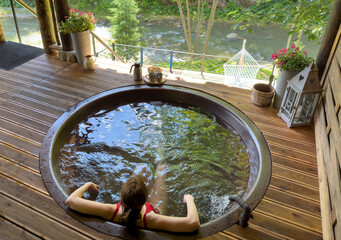 A girl relaxes in a cast-iron vat with mineral water and drinks tea against the backdrop of a...