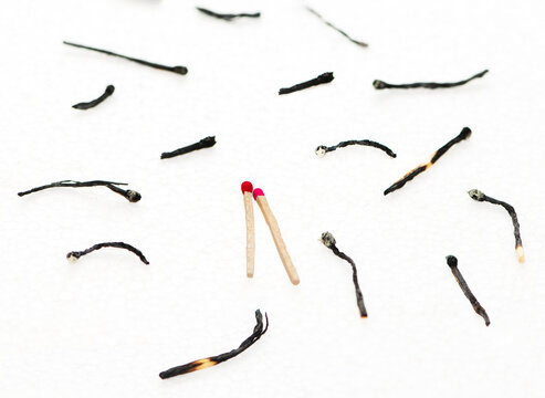 Two unused matchsticks surrounded by burnt matches to represent survival