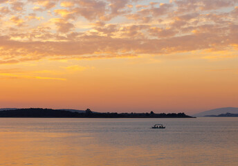 A boat sailing on a lake at the sunset