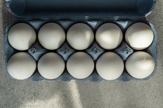 Overhead view of a cardboard egg carton filled with ten white eggs