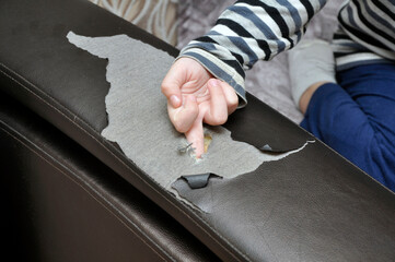 A child's finger pierces the sofa and makes a hole in it. Children's fun.
