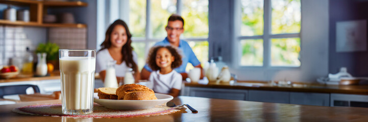 Happy family having breakfast at home. Focus on the glass of milk, panoramic image with copy space - 745294921