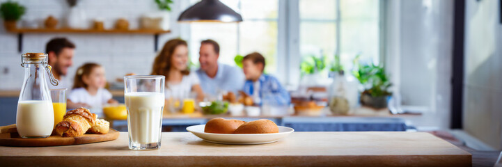 Happy family having breakfast at home. Focus on the glass of milk, panoramic image with copy space - 745294931