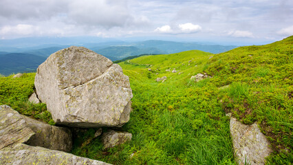 green alpine hills and meadow of carpathians. stones among the grass beneath a sky with clouds....