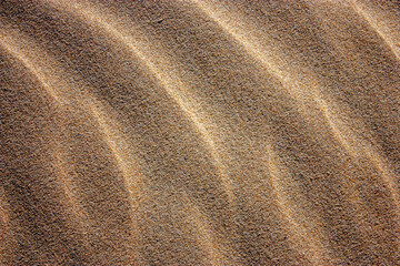 Waves on the surface of the sand, top view. The wavy surface of coastal sand. The structure of waves on sea sand.