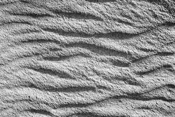 Waves on the surface of the sand, top view. The wavy surface of coastal sand. The structure of waves on sea sand.