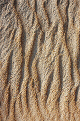 Waves on the surface of the sand, top view. The wavy surface of coastal sand. The structure of waves on sea sand.