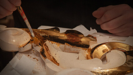 The artist craftsman gilds the ornament with real gold. Goldsmith. Hands and brush