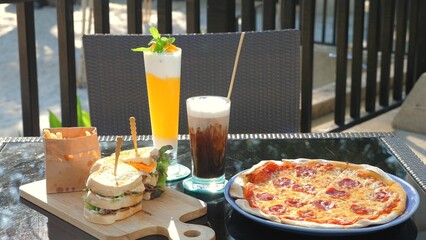 Al fresco dining setup featuring refreshing cocktail, gourmet sandwich, iced coffee, and savory pizza on sunny patio. Gastronomy and leisure.
