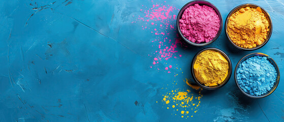 Obraz na płótnie Canvas Top view of colorful Holi powder in bowls on a blue background with copy space for text, Happy Holi festival banne