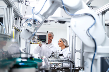 Technology specialists monitoring artificial intelligence of robotic machines inside the factory.