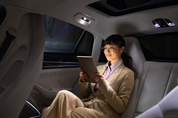 Wealthy Asian businesswoman going on business trip in luxury automobile while having conference...