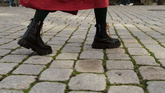 Girl Walking By Historical Part Of European City Strides Confidently On Cobblestones in Black Boots