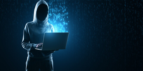 A mysterious figure in a hoodie in front of a laptop with binary code signifying a cyber attack or...