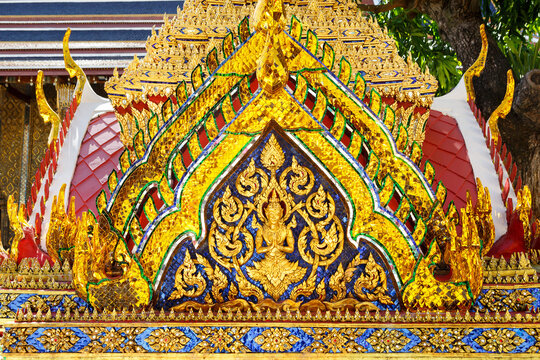 Beautiful pediment of a Buddhist temple decorated with golden images of the Buddha