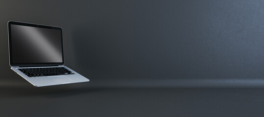 Silver laptop with a blank screen angled in a dark studio setting. Technology presentation concept....