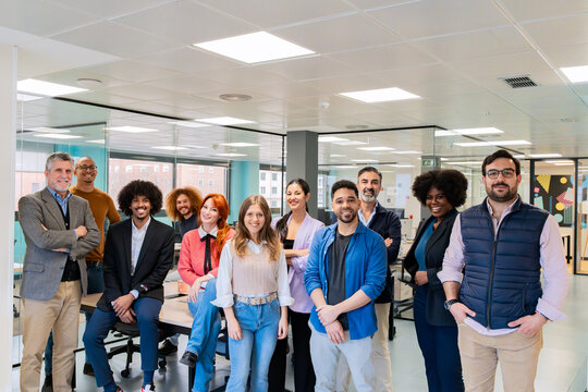 Diverse team of professionals posing together in a modern coworking office environment. 