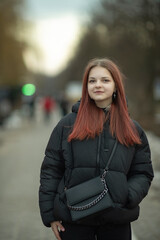 Obraz premium Portrait of a young beautiful long-haired girl on a spring city street.