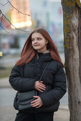 Portrait of a young beautiful long-haired girl on a spring city street.