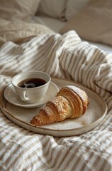 breakfast croissant and coffee on tray over bed