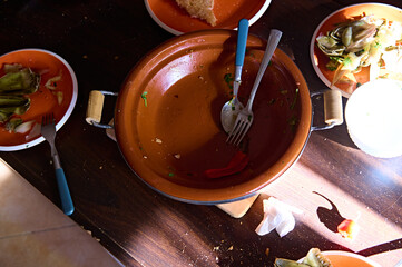 View from above of an empty dirty tagine and plates with the leftover of food after lunch or dinner