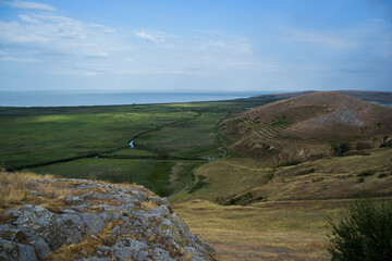 Country side view, green field, rocks, dunes, blue sky
