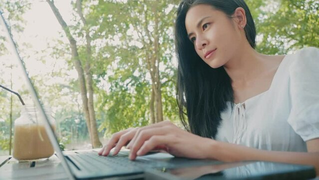 Asian woman doing online working with laptop computer, remotely communicate, positive emotion, work life balance, focus and concentration on the computer screen, workaholic asian female, hard work