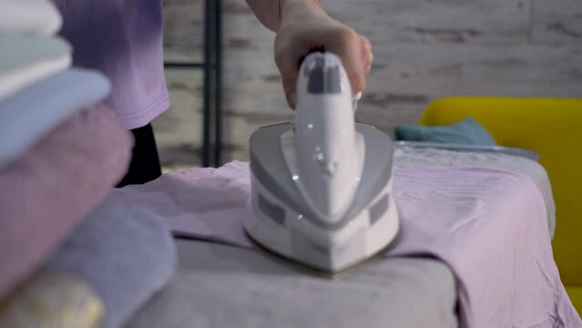The iron nose of the iron to the camera. The concept of successful ironing, a woman ironing clothes on an ironing board