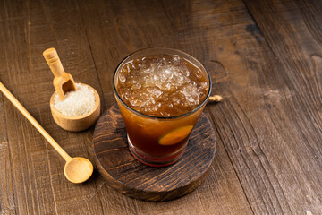 Traditional sweet iced lemon tea with honey and ice in small glasses on wood table

