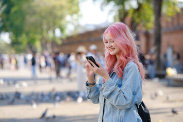 Outdoor portrait of pink hair cool girl texting on phone.