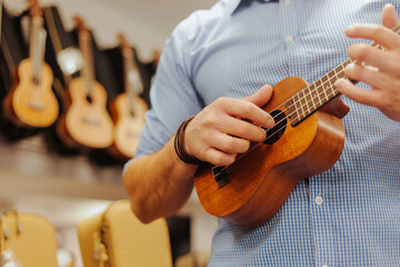 Young man musician or customer playing ukulele at music store