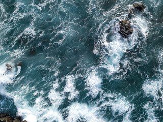 Fototapeta premium View from drone of Atlantic Ocean waves meeting with sharp underwater rocks. Sea waves crash on rocks with foam, south of Tenerife, Canary Islands