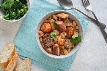 Tripas a Moda do Porto - pork Tripe stew with white beans and smoked sausages on the white table. Flat lay