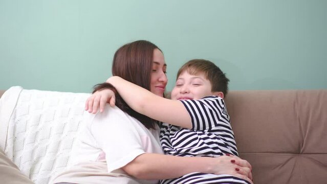 Cute son kisses mom. Happy little boy hugging his mother at home. Loving mum and kid cuddling embrace cheerful to family holiday event.Concept love mom.