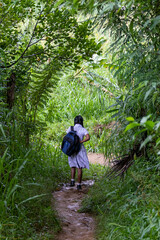 chica volviendo de la escuela por la selva