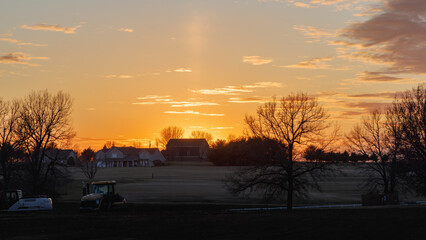 sunset over farmhouse with field in the foreground